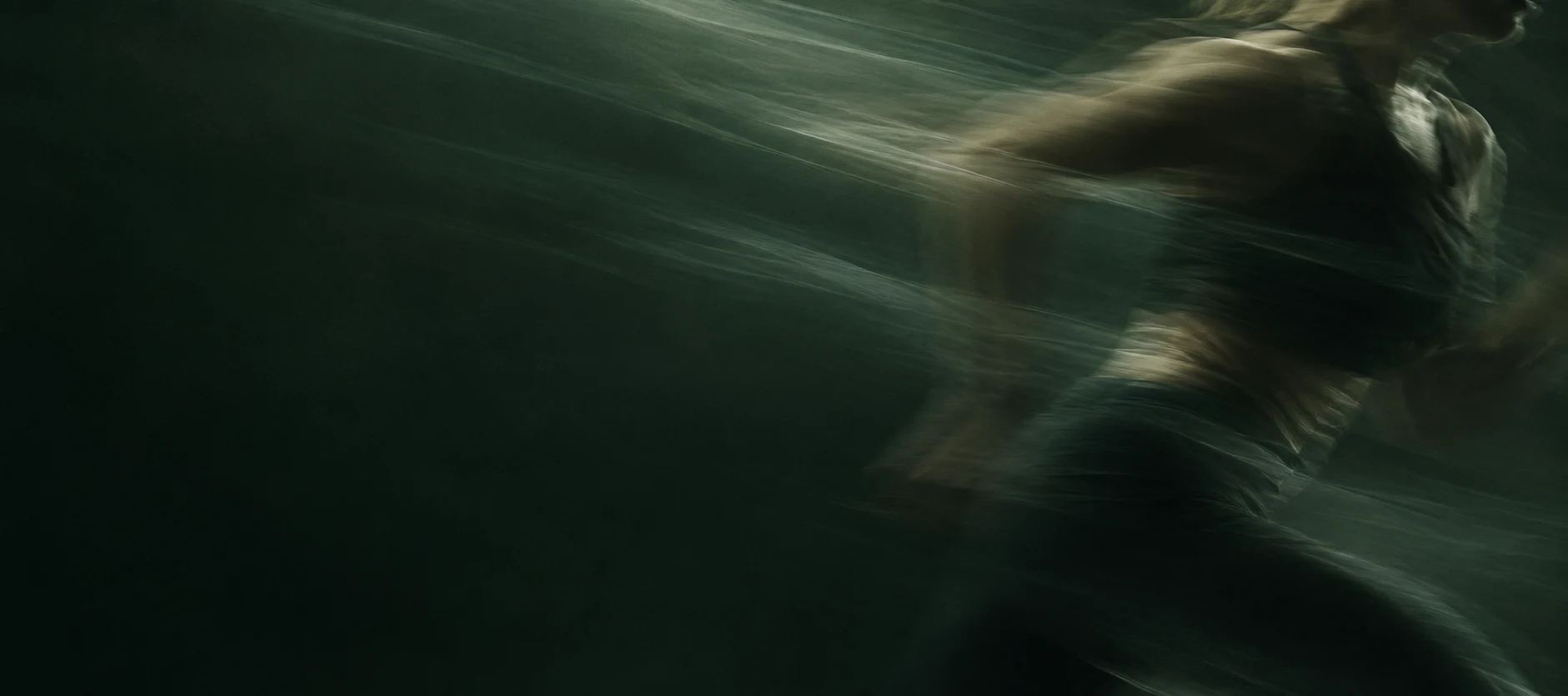 A runner in motion against a blurred forest backdrop.